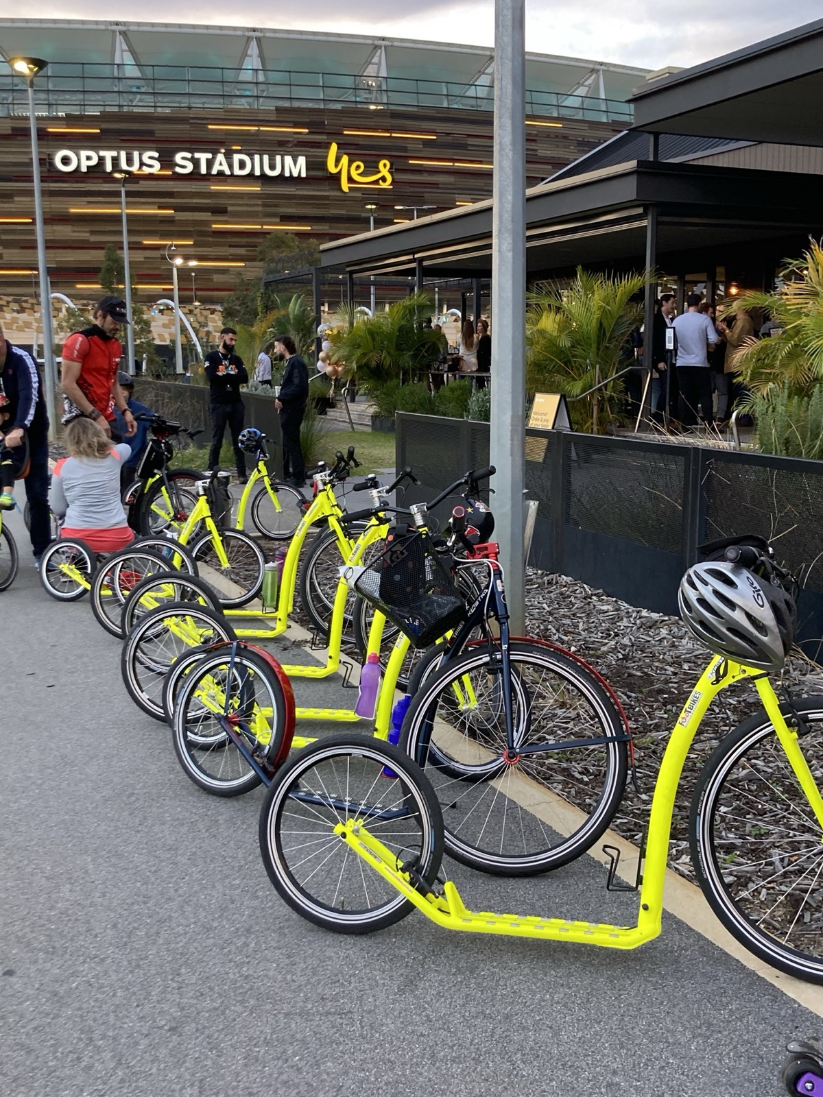 A row of yellow footbikes parked outside Optus Stadium in Perth